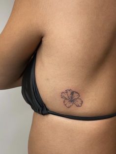 a woman's stomach with a small flower tattoo on her left side ribcage