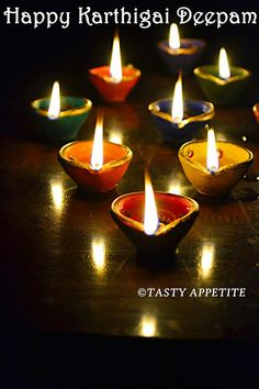 happy kartirigai deepam with lit candles in bowls on a table