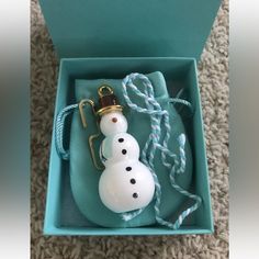 a snowman ornament in a blue box on the floor next to a string