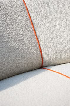 an orange cord is attached to the back of a white couch with fabric on it