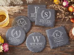 four personalized slate coasters on a wooden table