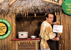 a man holding a sign in front of a hut