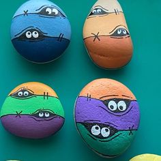 four painted rocks with faces on them sitting next to each other in front of a green background