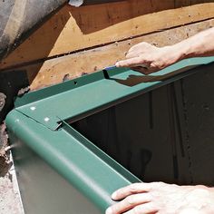 a man is working on the side of a green window