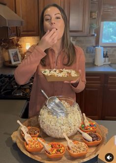 a woman standing in front of a table filled with bowls and containers full of food