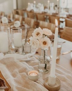 the table is set with candles and flowers in glass vases on top of linen