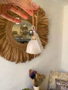 a hand holding a small bell ornament in front of a mirror with a price tag hanging from it