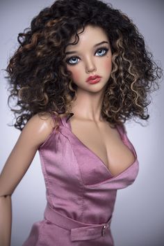 a close up of a doll with curly hair and blue eyes wearing a pink dress