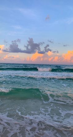 the ocean waves are rolling in to shore at sunset with clouds and blue sky above