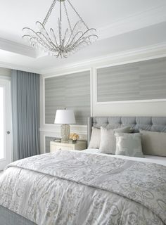 a bedroom with a chandelier hanging from the ceiling and two lamps on either side of the bed