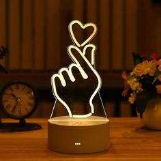 a light that has a hand holding a heart in it on top of a table