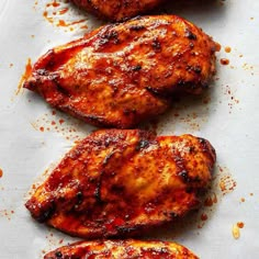 three pieces of grilled chicken sitting on top of a piece of white parchment paper