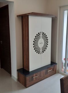 a cabinet with an intricate design on the front and side, sitting in a room next to a window