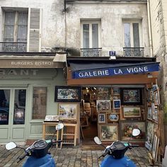 two mopeds parked in front of a building with paintings on the walls and windows