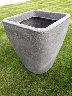 a concrete planter sitting on top of a lush green field