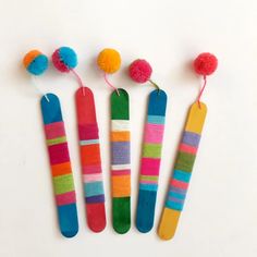 four different colored toothbrushes with pom - poms attached to them on a white surface