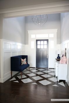 a blue chair sitting on top of a hard wood floor next to a white door