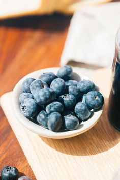 a bowl of blueberries next to a glass of juice