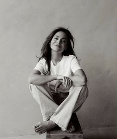 a woman sitting on top of a suitcase smiling