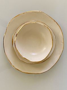 three white and gold plates stacked on top of each other