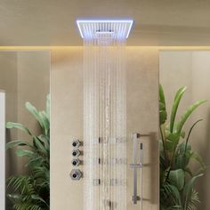 a shower head with water running down it's side and plants in the background