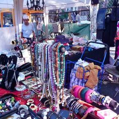 an outdoor flea market with beads and other items on the ground, including necklaces