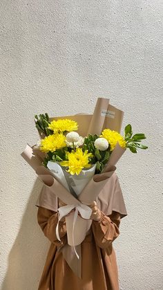 a woman holding a bouquet of yellow flowers