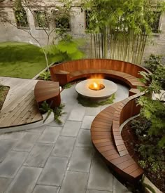 an outdoor fire pit in the middle of a garden with wooden benches and plants around it