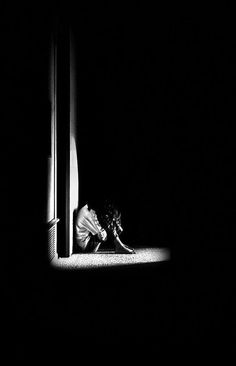 black and white photograph of a woman sitting on the floor in front of a window