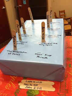 a table topped with a blue box covered in paper and wooden clothes pins that spell out the names of jesus