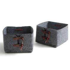 two gray storage baskets with handles on each side and brown leather straps at the top