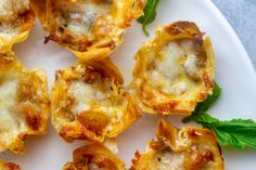 several mini pizzas with cheese and spinach leaves on a white plate, ready to be eaten