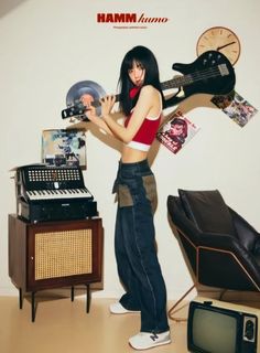 a woman holding an electric guitar in front of a record player and other musical equipment