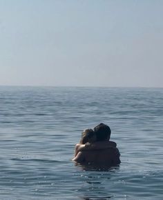 two people are in the water hugging each other and looking out at the ocean on a sunny day