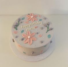 a birthday cake decorated with flowers and the words happy birthday roma on it's side