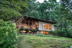 a large house sitting on top of a lush green hillside next to trees and bushes