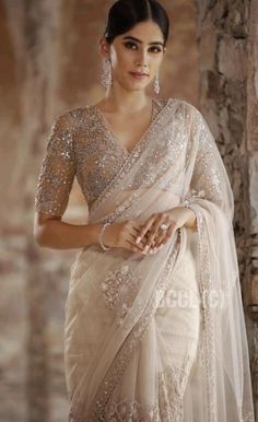 a woman wearing a white sari with sequins on the blouse and sleeves