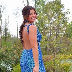 a woman in a blue dress is smiling and posing for the camera with her hand on her hip