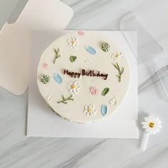 a birthday cake with flowers on it sitting on top of a table next to a card