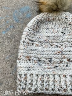 a white knitted hat with a brown pom - pom sitting on top of it