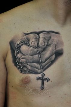 a chest tattoo with a rosary and hands holding a cross