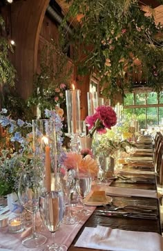 a long table with flowers and candles is set for a formal dinner in an elegant setting