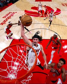 the basketball player is going to dunk the ball into the hoop while other players watch