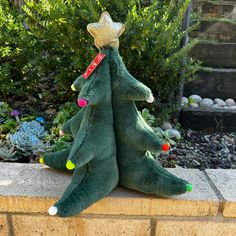 two green christmas trees sitting on top of a brick wall