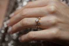 a close up of a person wearing a ring with two stones on it's finger