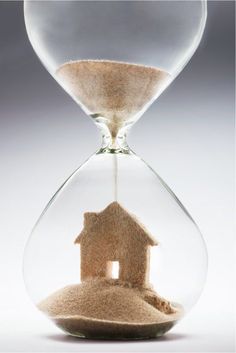 an hourglass with a house in it and sand falling out of the top half