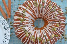 a bundt cake with white icing and pistachios on top next to a plate