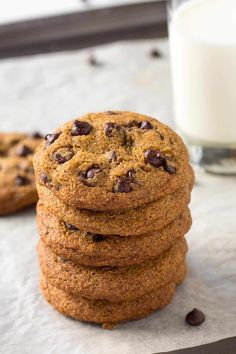 chocolate chip cookies stacked on top of each other next to a glass of milk,