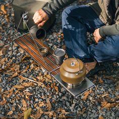 a man is sitting on the ground with his coffee pot