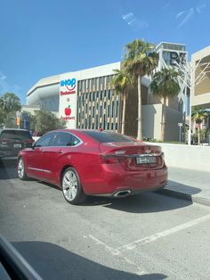 a red car is parked in front of an apple store with palm trees behind it